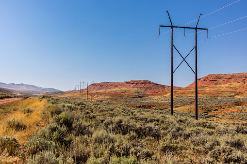 Hot Springs County, Wyoming. Power line, with poles and cables, on the prairie, along a dirt road that runs around Copper Mountain, frequently changing its name, and connects several ranches between Shoshoni and Thermopolis.