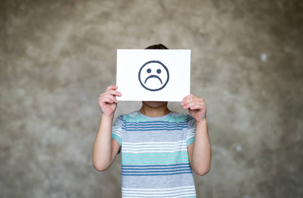 istock Boy holding paper with sad face 1312831579