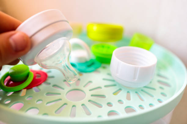 a man installs a pacifier from a baby feeding bottle into a sterilizer - sterilizer imagens e fotografias de stock