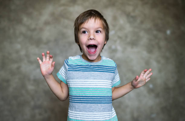 Smiling boy whit raised hands against colored background