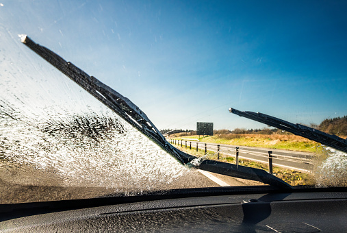 Windscreen wipers clearing away washing fluid for better visibility on a journey.