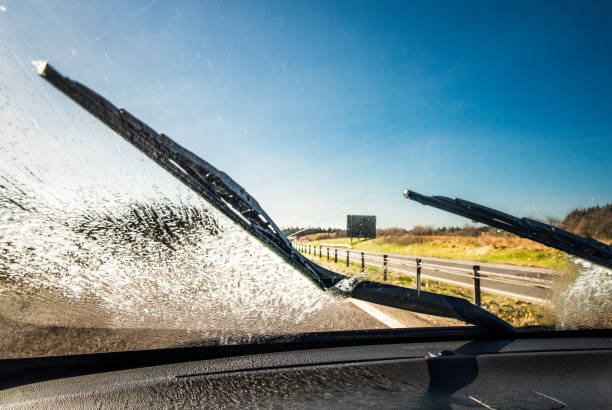 Clearing the windscreen while driving Windscreen wipers clearing away washing fluid for better visibility on a journey. windshield wiper photos stock pictures, royalty-free photos & images