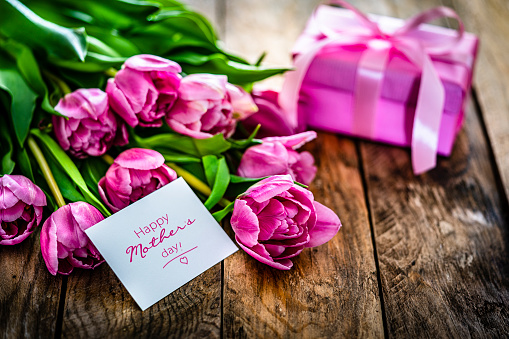 Close up view of pink tulips bouquet and a greeting card with the text 