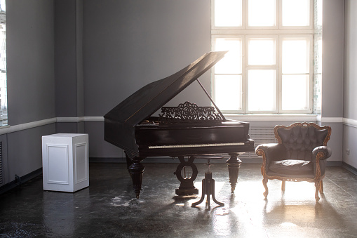 black antique grand piano in the interior with beautiful light from the window. High quality photo