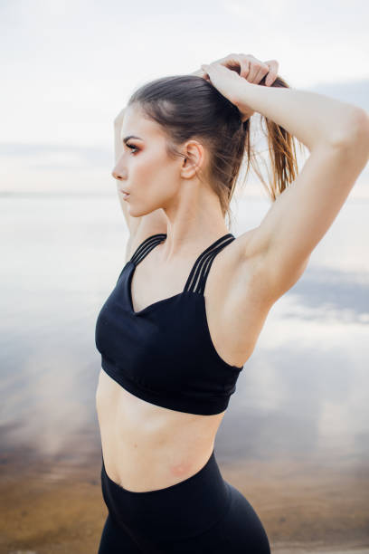 istock athletic girl with tank top doing a stretch on the beach 1312849853