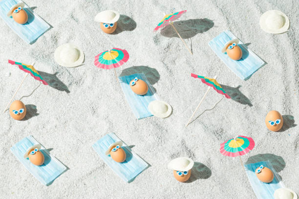 istock Summer Easter pattern background with eggs, virus mask, beach umbrella and glasses. Minimal pandemic or holiday concept. Safe distance. Top view. 1312849927