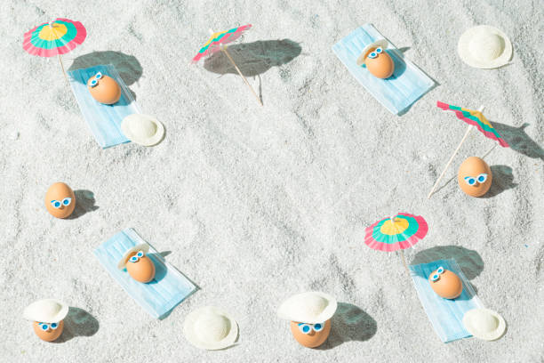 Summer Easter pattern background with eggs, virus mask, beach umbrella and glasses. Minimal pandemic or holiday concept. Safe distance. Top view.