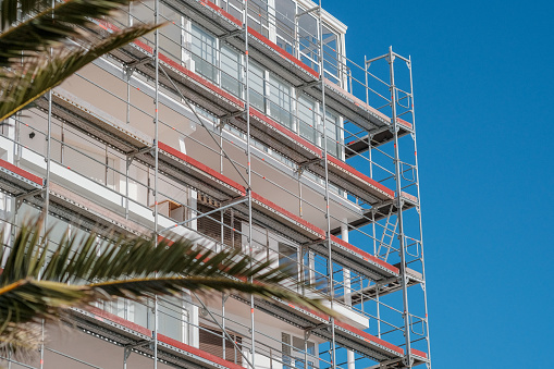 Renovation of facade of a hotel in European resort on palm trees and blue sky background