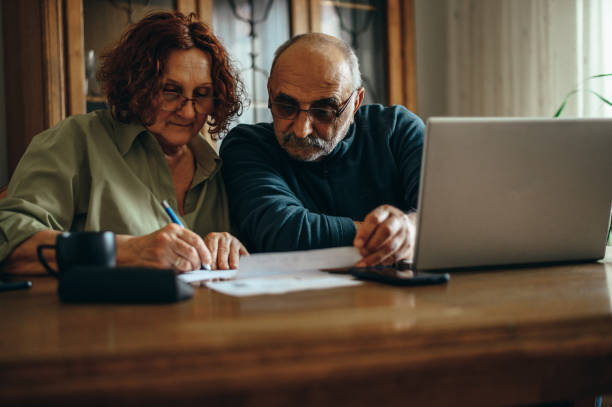 istock Senior couple doing finances while using a laptop at home 1312858211
