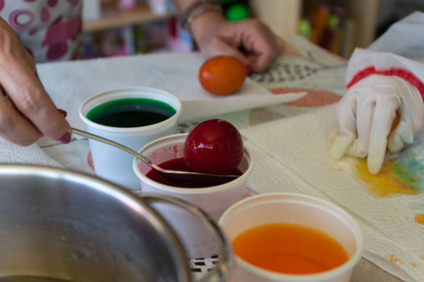 istock Little girl dyes easter eggs with her mother. 1312859033