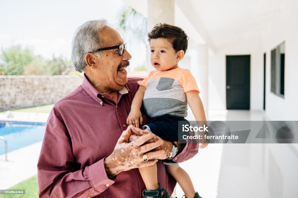 Grandfather holding grandson toddler by the swimming pool Grand father holding grandson Latin American and Hispanic Ethnicity Stock Photo
