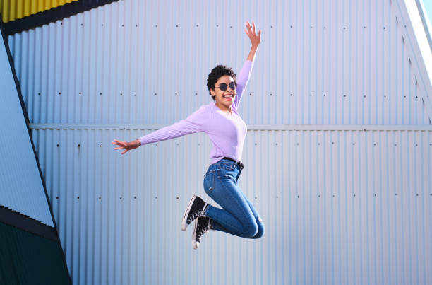 istock smiling young afro woman jumping 1312865682