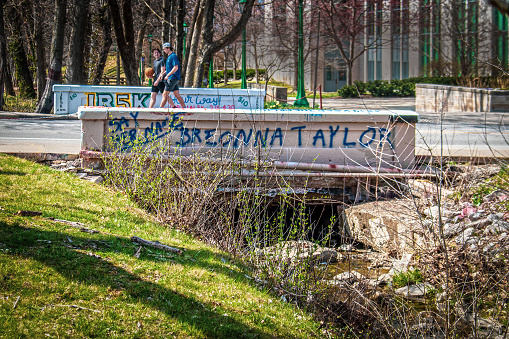 03_04_2021 Bloomington USA Two University students with a basketball cross concrete bridge with Breonna Taylor spray painted on it  near university campus.