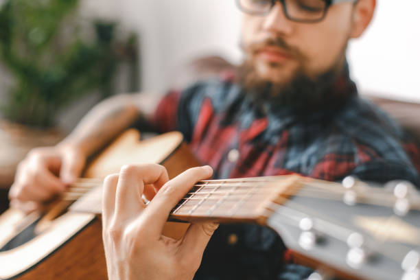 istock Young guitarist hipster at home with guitar holding strings close-up 1312878396