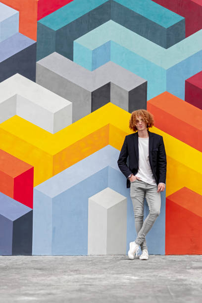 istock Trendy young man standing near colorful wall 1312878639