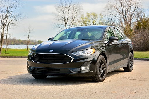 Dover, Wisconsin - USA - April 16, 2021:  The last of the 2020 Ford Fusion car models.  The Agate Black car has black wheels, fog lights, and blacked out grille. In a parking lot at Eagle Lake Park.