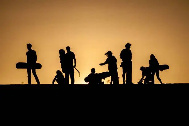 Silhouettes of sand boarders during the sunset near desert oasis Huacachina near Ica, Peru