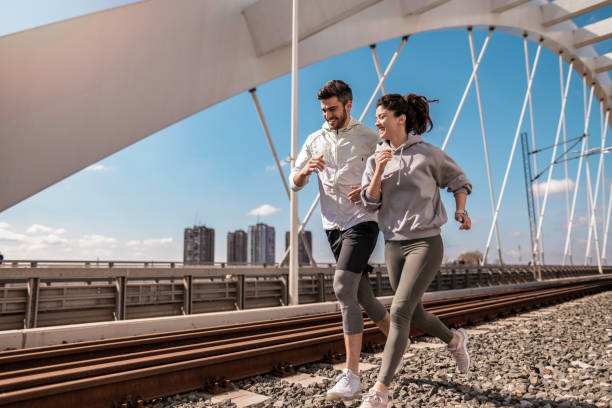istock Happy young athletic couple running on bridge. 1312888817