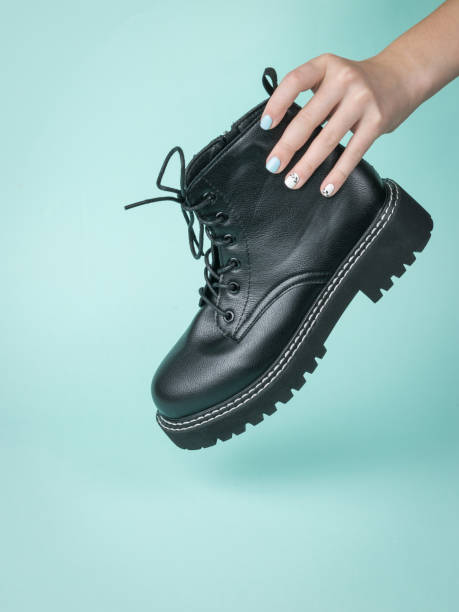 istock A woman's hand holds a brutal leather shoe on a blue background. 1312899366