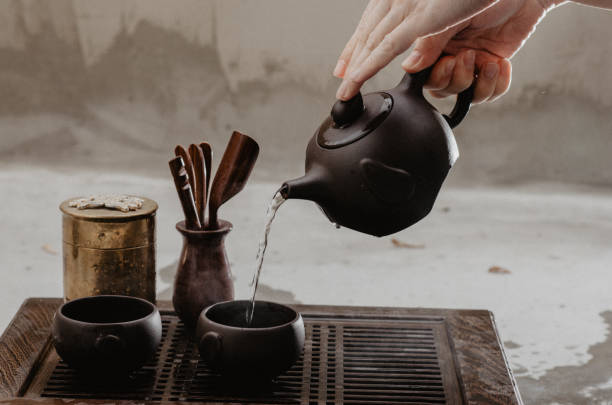 colpo ritagliato di donna che versa il tè nelle tradizionali teaware cinesi - chinese tea foto e immagini stock