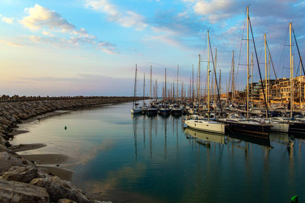 Marina is a specially equipped harbor for yachts, boats and small boats in Herzliya, Israel. Evening twilight on the Mediterranean Sea. Walk along the breakwater