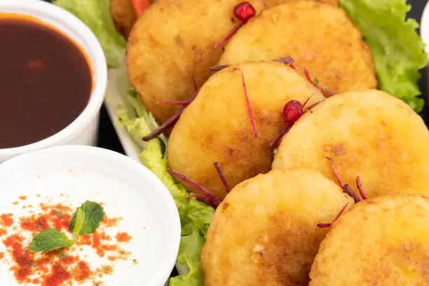 Photo of Indian Chaat Masala Snacks Aloo Tikki Also Known As Alu Ki Tikkia A Seasoned Boiled Mashed Potato Cutlet Or Patties Served With Fresh Chatpata Imli Tamarind Chutney Sauce And Spiced Dahi Curd