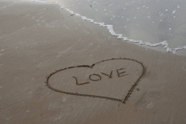 istock Hand drawn heart on beach. Romantic composition. a romantic background with copy space 1312908770