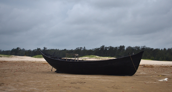 A traditional boat for fishing on Digha beach with clear skies on the shores of the Indian ocean. A boat brought ashore abandoned after a day of fishing.