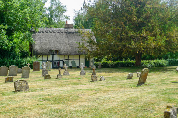River Thames: Graveyard at Dorchester Abbey with leaning gravestones and thatched cottage.