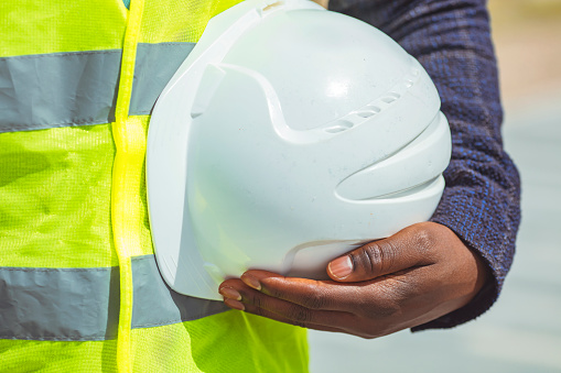 Engineer holding helmet at road construction site with machinery background,safety first concept. Engineering Construction holding white helmet blueprint at Construction background