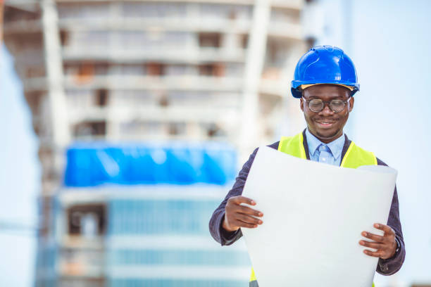 istock Portrait of construction inspector posing with blueprints on building site. 1312913881