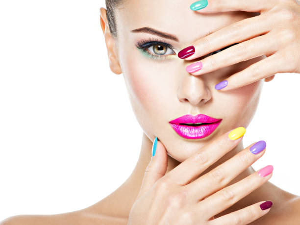 Close-up face of a beautiful woman  with colored nails and pink lips .