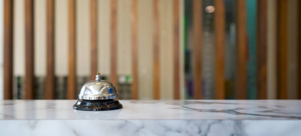 Closeup of a silver service bell on hotel reception desk. Closeup of a silver service bell on hotel reception desk. receptionist stock pictures, royalty-free photos & images