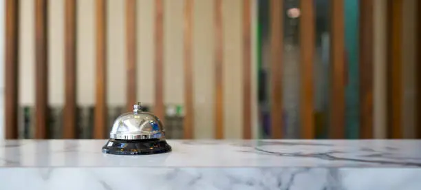 Photo of Closeup of a silver service bell on hotel reception desk.