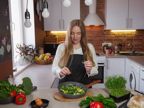 istock A young happy lady standing in the kitchen while cooking. 1312917862