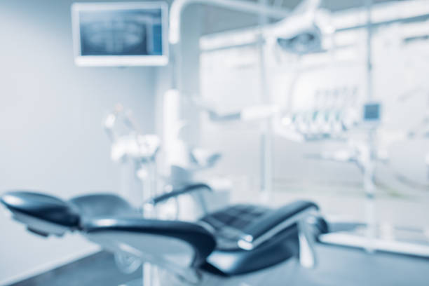 歯科医の椅子および器材が付いている歯科事務所の焦点が下がった背景およびコピースペースイメージ - 歯科医師 ストックフォトと画像