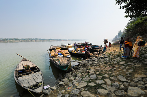 Katwa WB India - January 18, 2020 : Taken this picture of the bank of river Ganges at Katwa state West Bengal India. In the picture the boats are anchored beside the bank of river. The boats are getting loaded with goods and natives also waiting on boat for crossing of river.