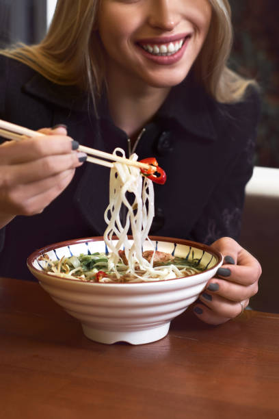 istock Female hands hold a bowl with Asian traditional soup. Beef pho bo with eggs. 1312925310