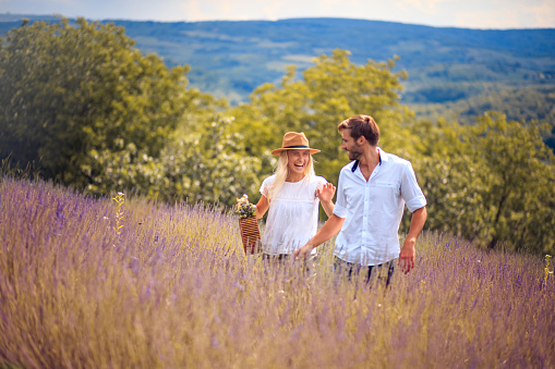 Mother with her little daughter and son walking on a meadow outdoors in sunset.