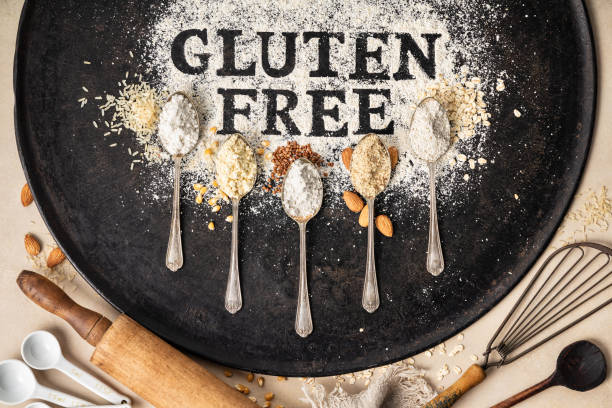 Gluten free written in flour on vintage baking sheet and spoons of various gluten free flour almond flour, buckwheat flour, rice flour, corn flour, oatmeal flour , flat lay, top view stock photo