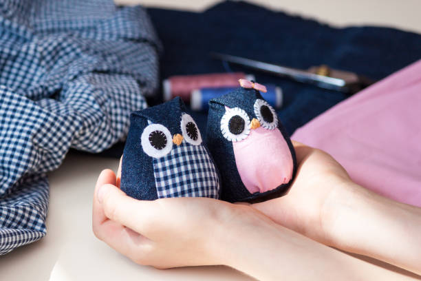 Child holds in his hands hand made owls. Craft tools and materials on the table.