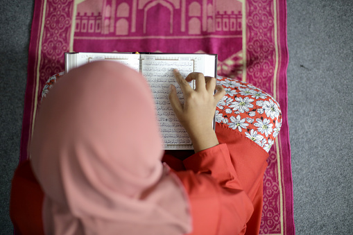 A Muslim girl is reading Quran (koran - holy book).