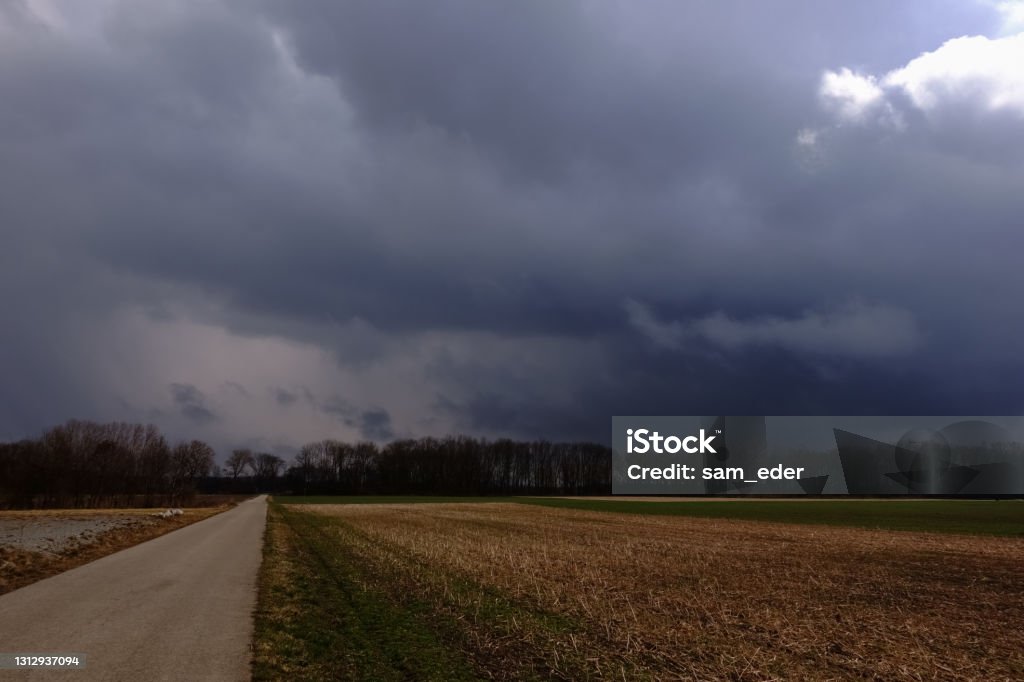 dirt road with fields and dark rain clouds long dirt road with fields and dark rain clouds Color Image Stock Photo