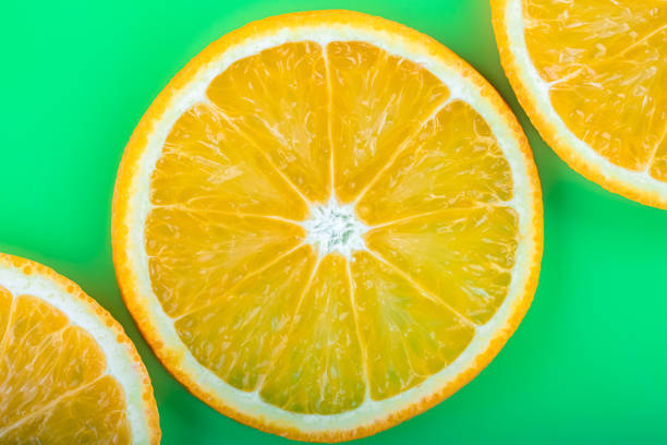istock Bright tropical summer pattern with orange fruit close-up on green background. Juicy citrus slices, vitamin C concept, fun abstract wallpaper, art banner. Healthy food and drink. 1312938163