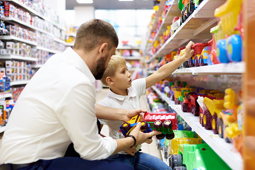 A dad with a small child is shopping at a children's store.