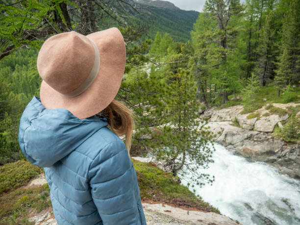 istock Young woman on mountain trail contemplating waterfall 1312941391
