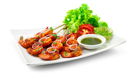 Tandoori Shrimps Grilled Skewers served Mint Sauce is a classic Indian dinner that marinates Shrimps wing in a creamy yogurt base, blended spice decorate with Onion,Lime and vegetable sideview