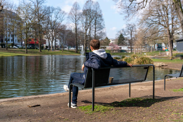 istock Young man sitting on park bench 1312948597