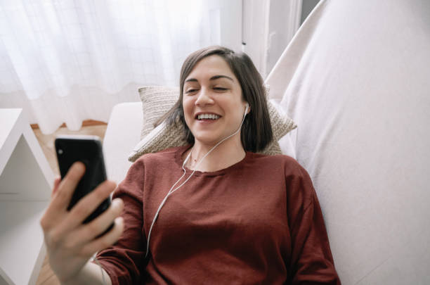 istock Smiling woman having a video call with her smartphone on the sofa 1312948798