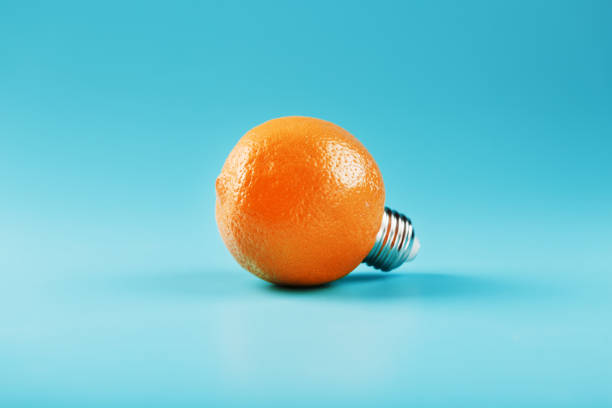 istock Orange light bulb on a blue background. The concept of fruit ideas 1312951257